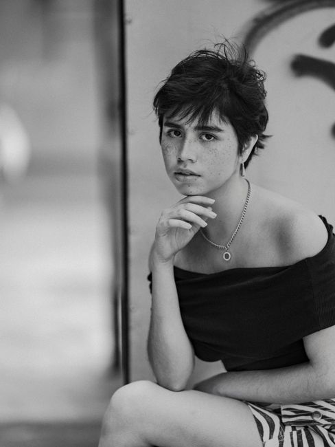 Artistic portrait of a young woman with freckles, captured in black and white, showing emotion and style.