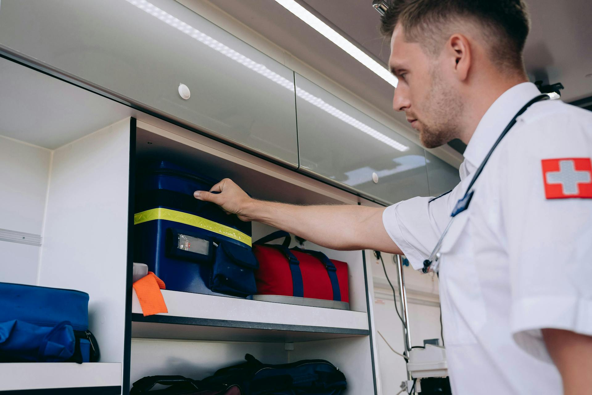 Paramedic Grabbing a Bag with a Medical Kit from the Shelf in the Ambulance