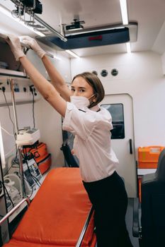 Paramedic adjusts equipment inside an ambulance, demonstrating readiness for emergencies.
