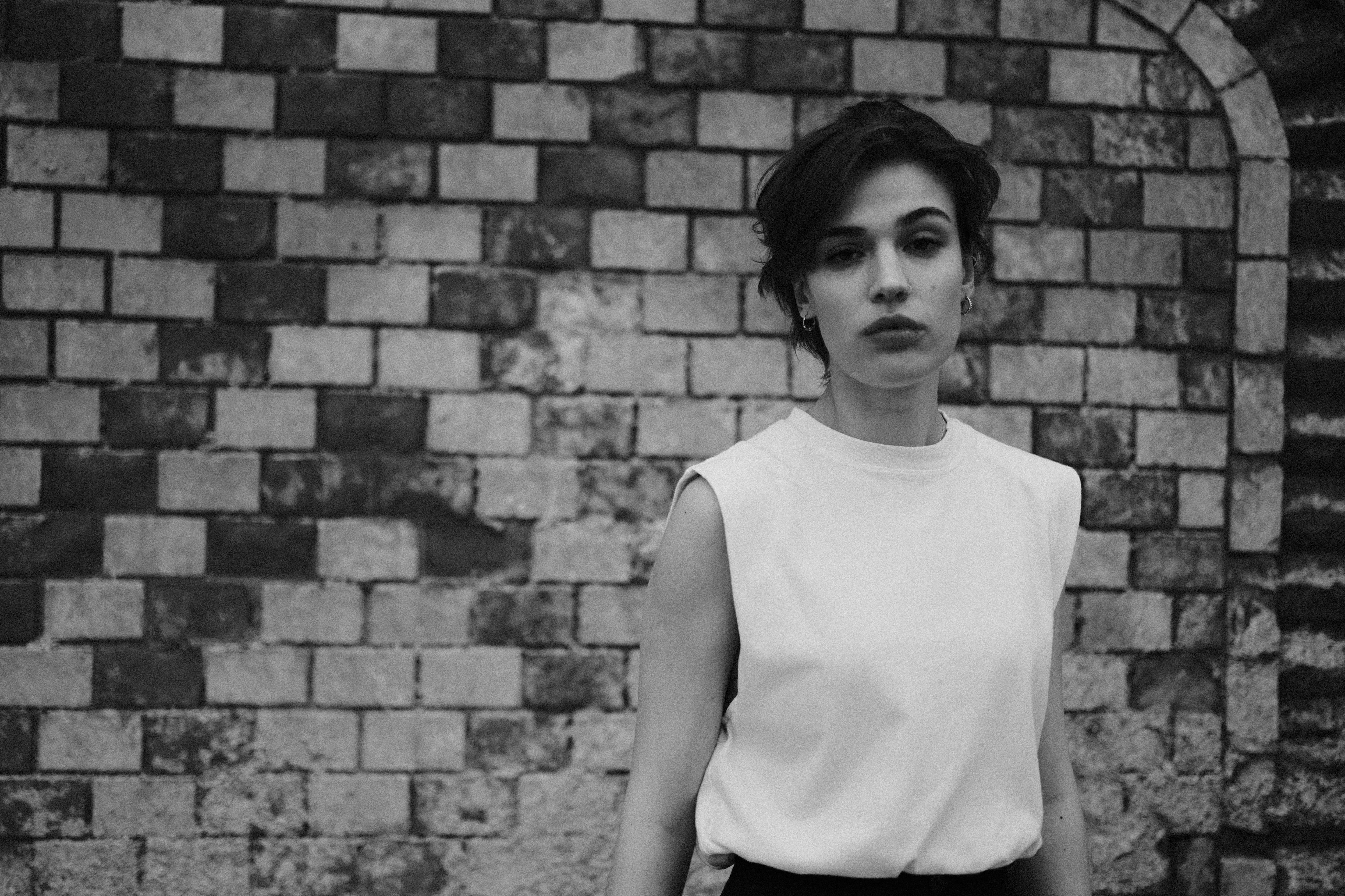 A woman in a white shirt and black pants standing in front of a brick ...