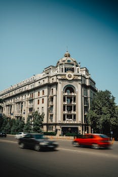A classic urban building with cars in motion on a sunny day, showcasing architectural charm.
