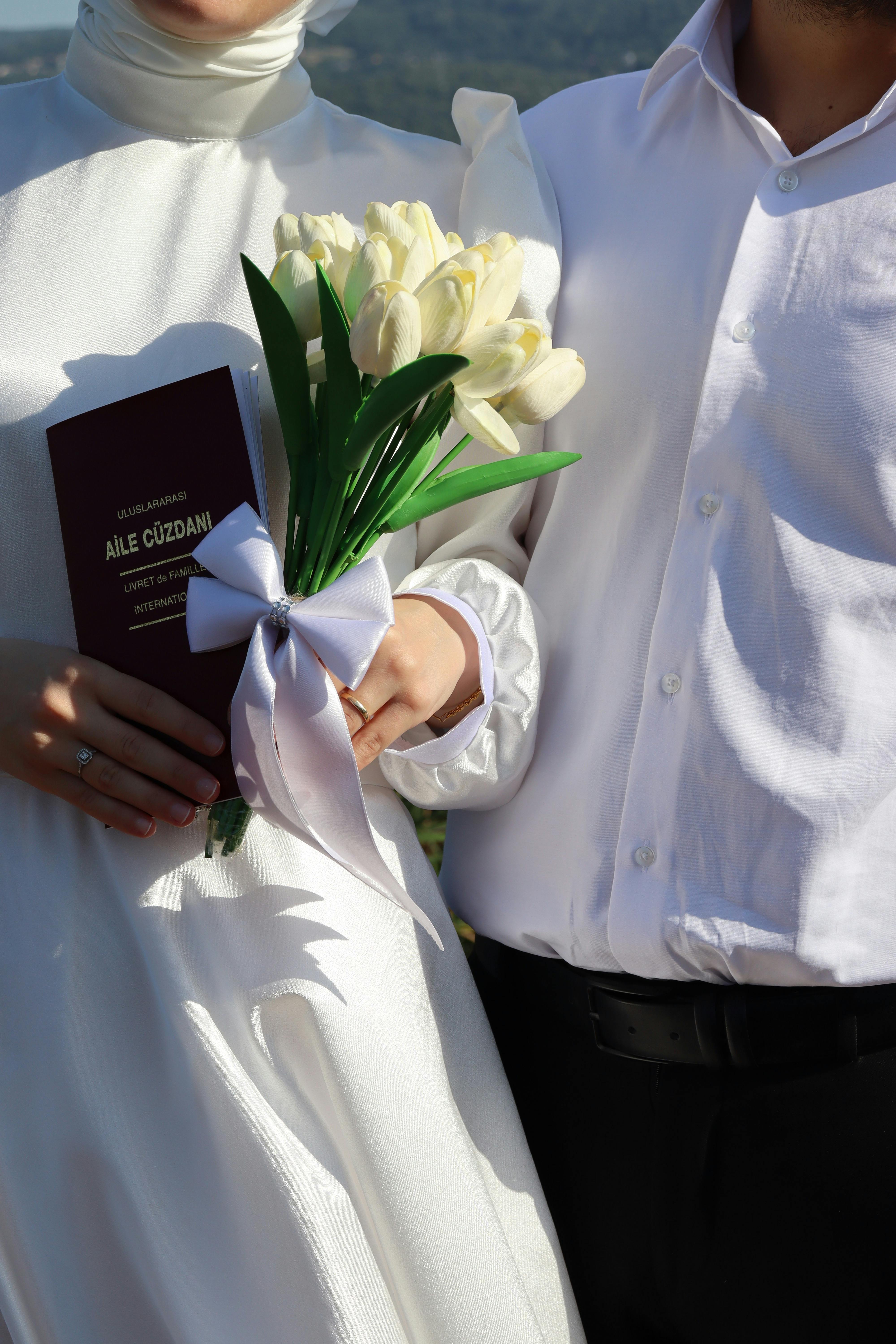 Couple holding a marriage certificate and bouquet, symbolizing love and union.