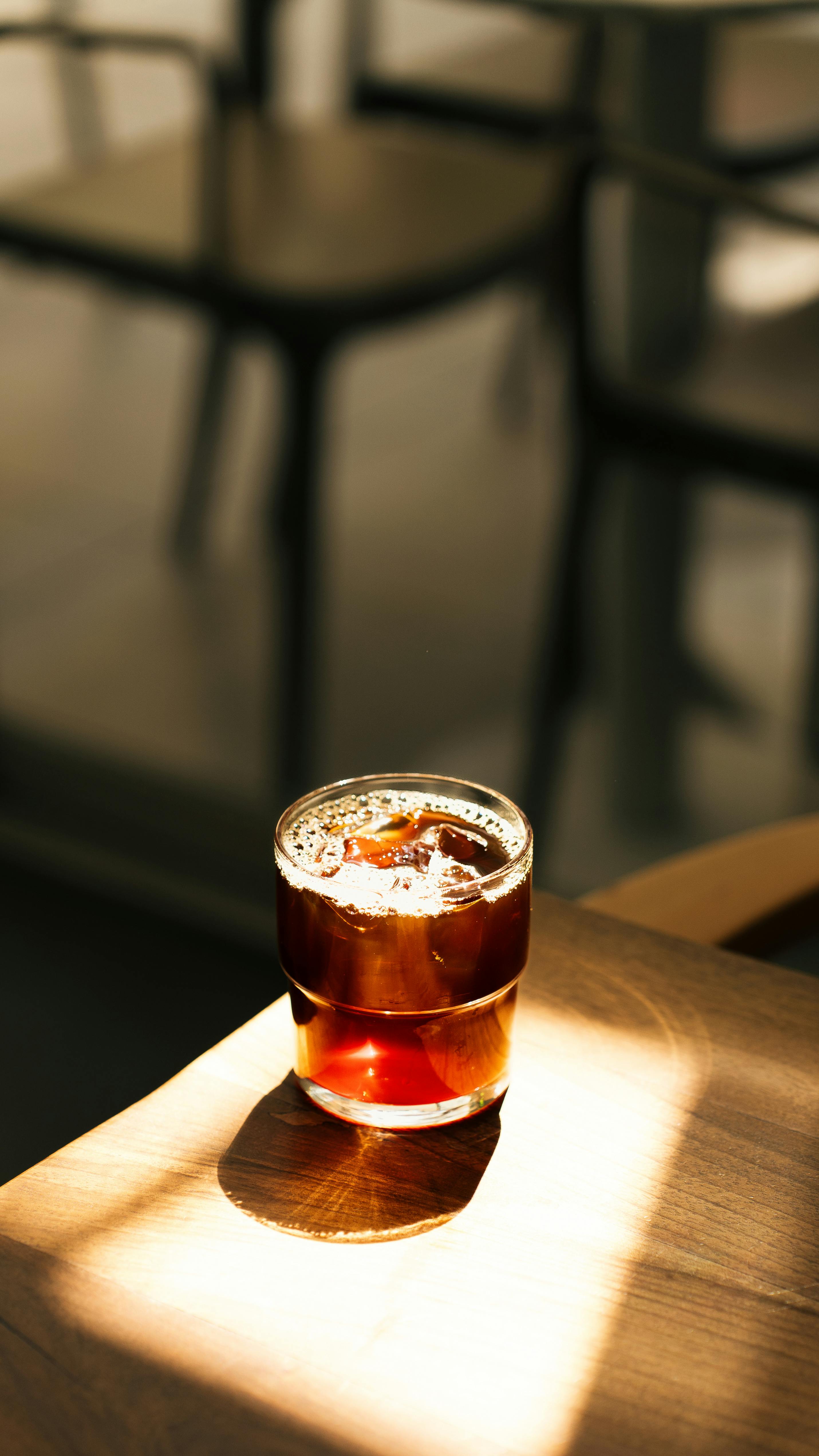 A glass of refreshing cold brew coffee on a sunlit wooden table, perfect for a cozy cafe ambiance.