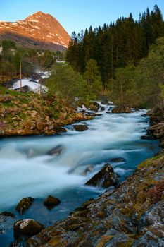 Breathtaking view of a waterfall in Geiranger, Norway surrounded by lush greenery and mountains.