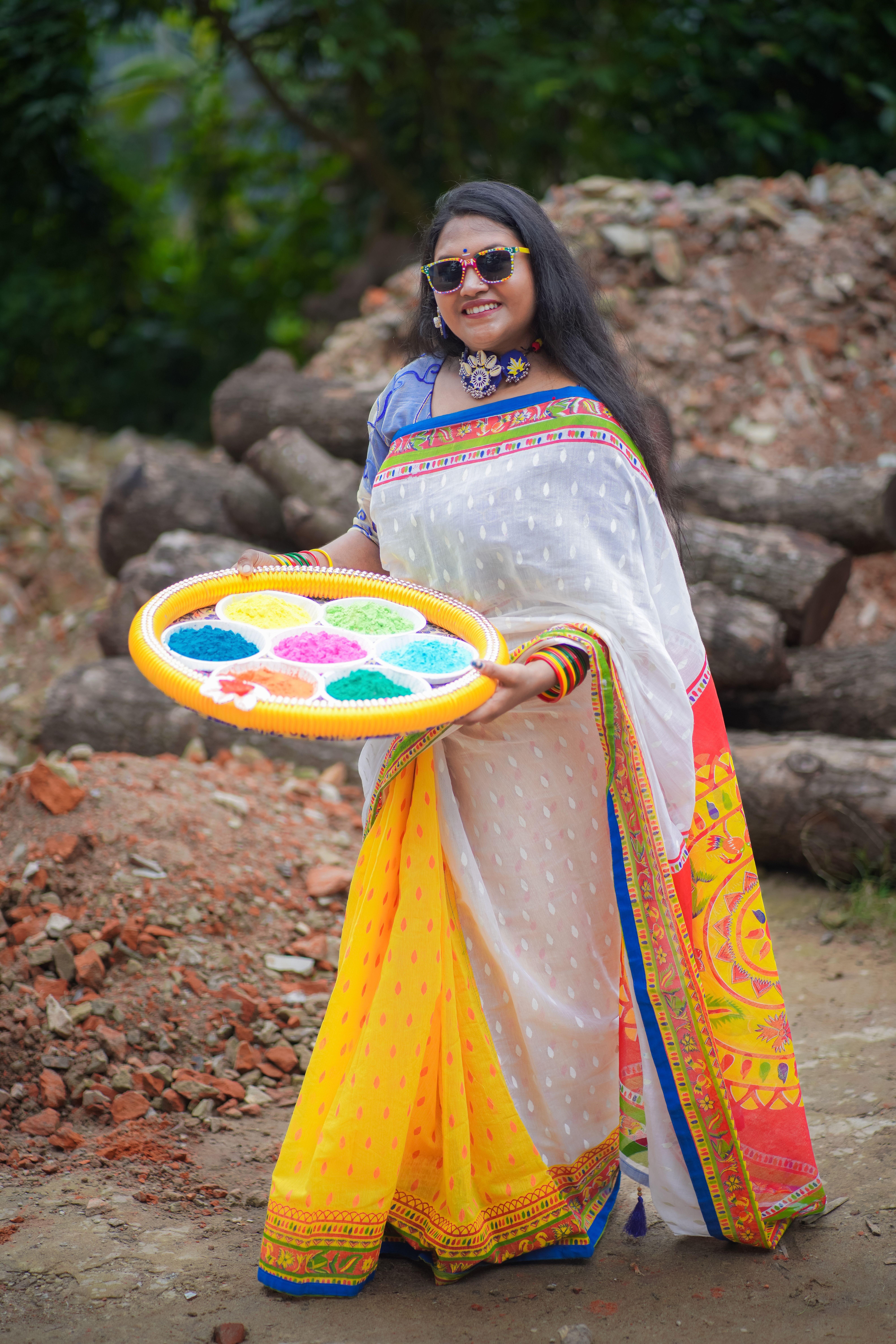 South Asian woman celebrates a color festival, smiling in traditional attire outdoors in Bangladesh.