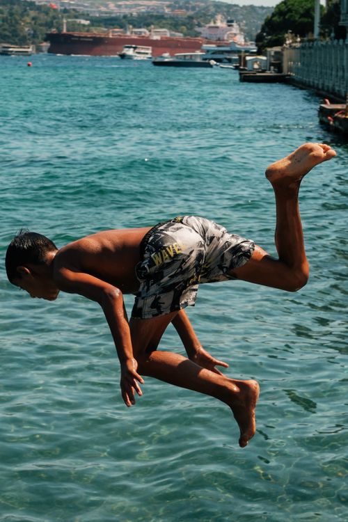 Free Exciting moment of a boy jumping into Istanbul's waters. Perfect for summer fun imagery. Stock Photo