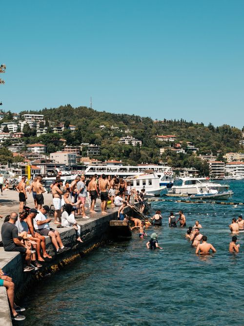 Free People enjoying a sunny day by the seashore in İstanbul, Türkiye, with boats and vibrant scenery. Stock Photo