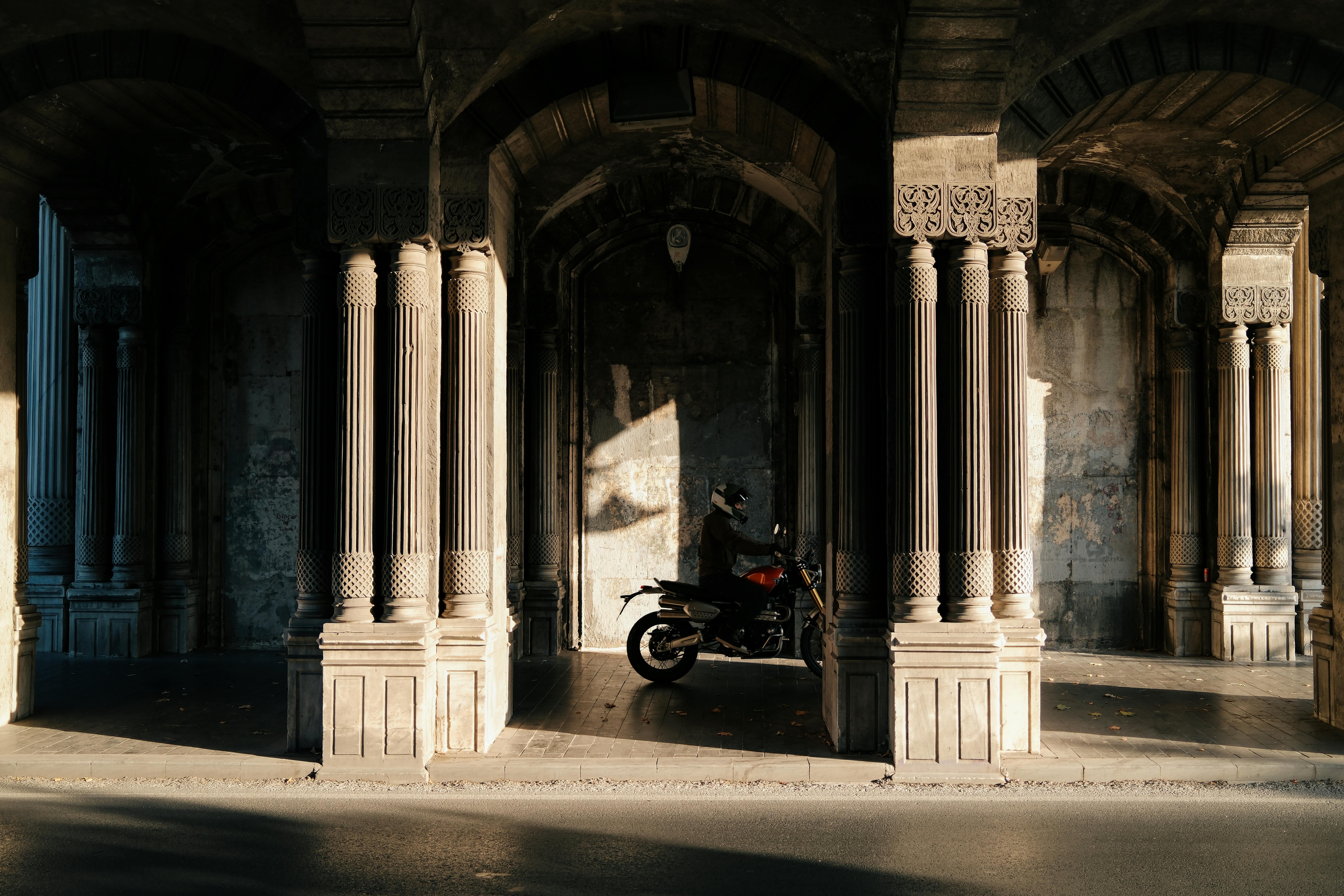 A motorcycle rides through an illuminated historic archway in Istanbul.