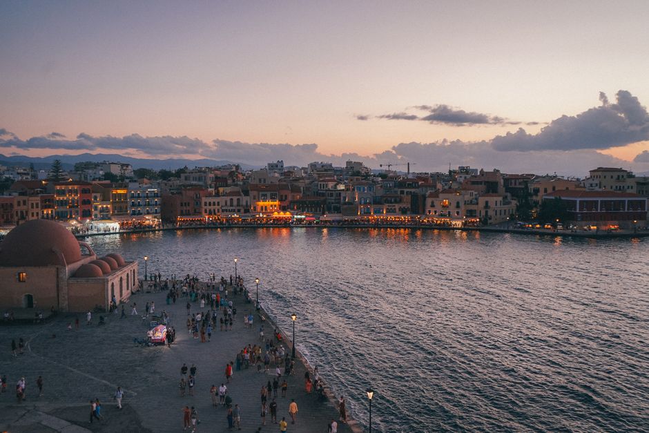 A picturesque sunset view of Chania waterfront in Greece with bustling promenade and tranquil sea.