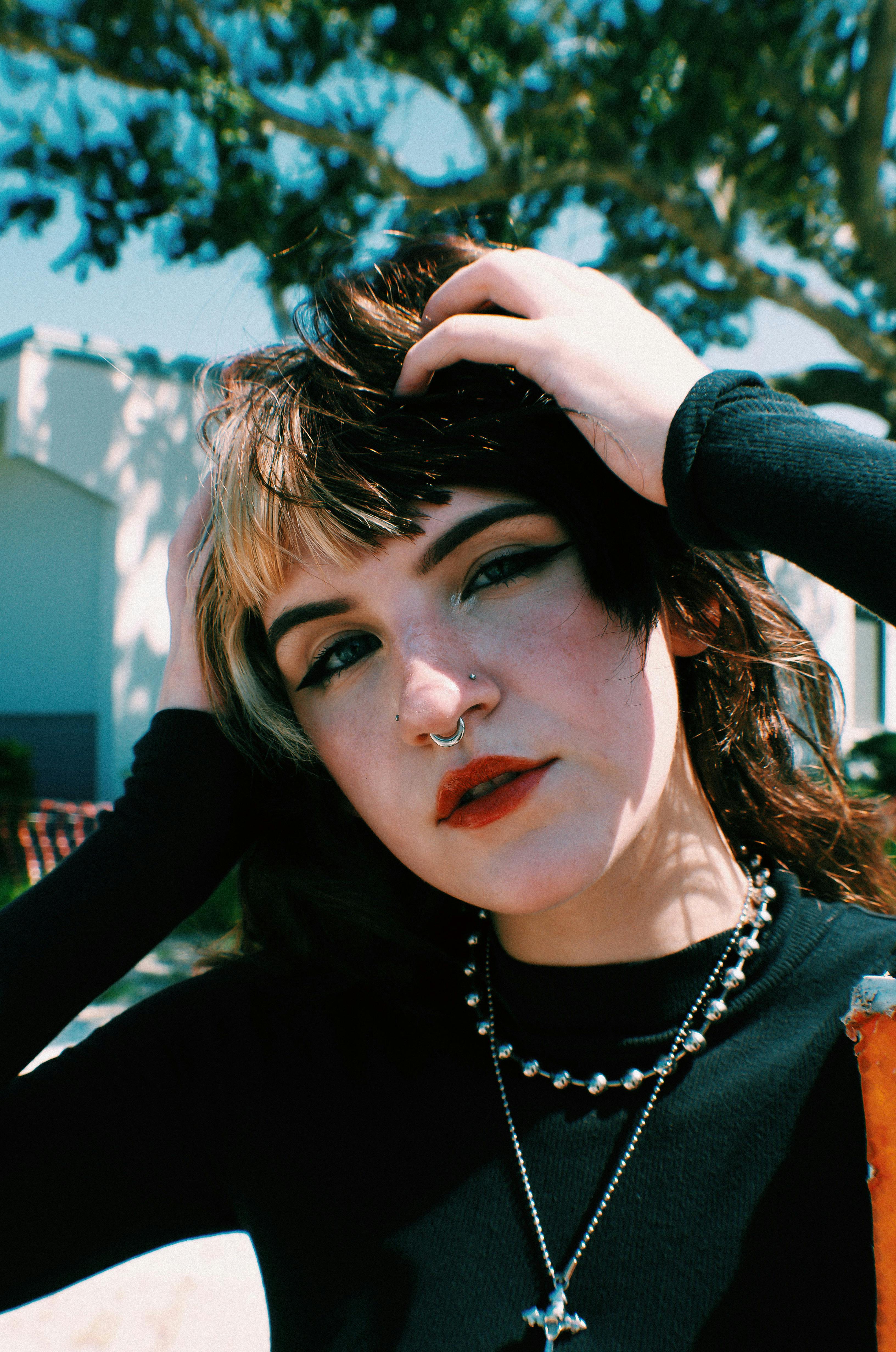 Portrait of a stylish young woman in a black top posing outdoors with bold accessories.