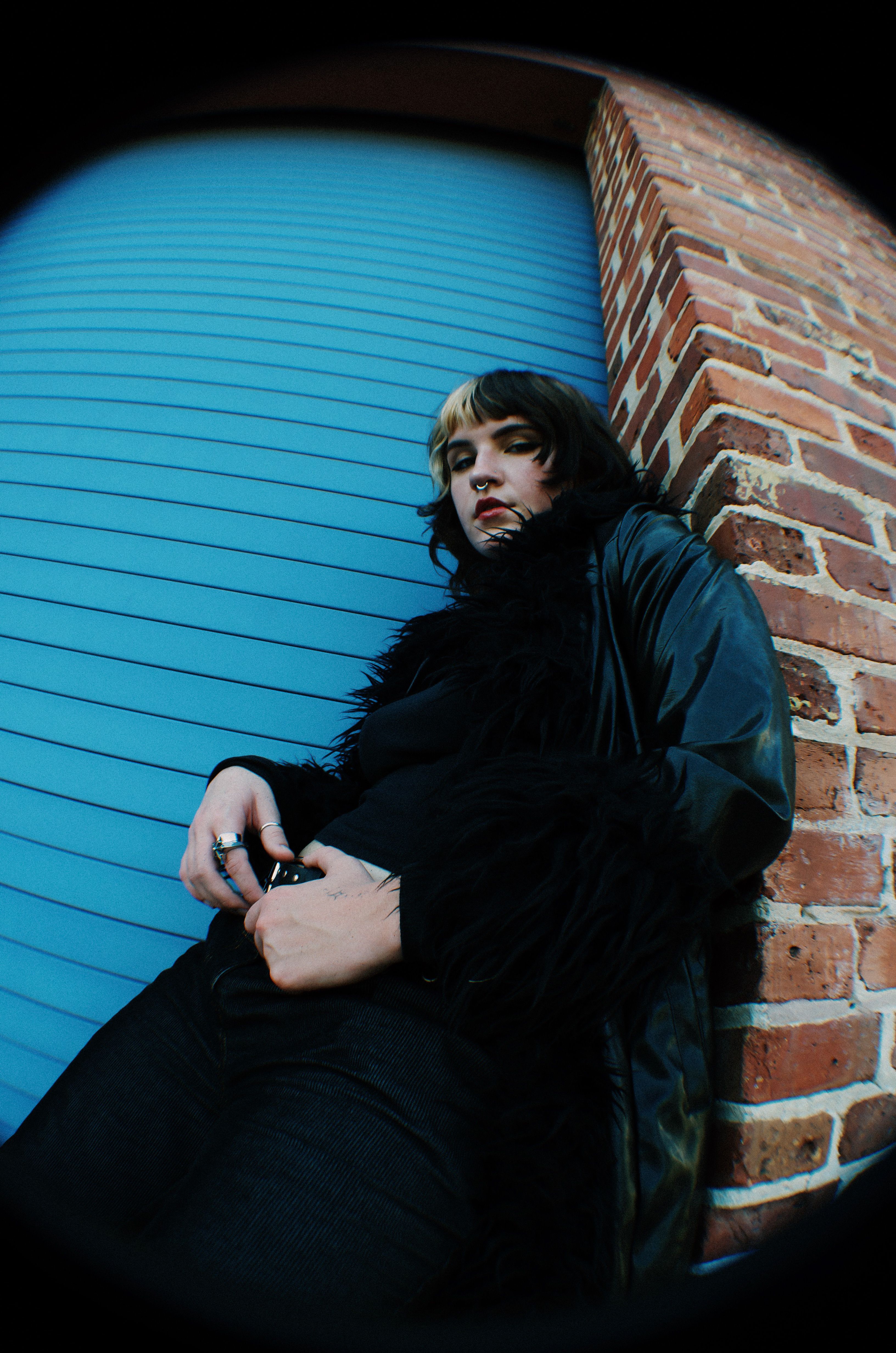 A woman leaning against a blue wall with her hand on her hip · Free ...