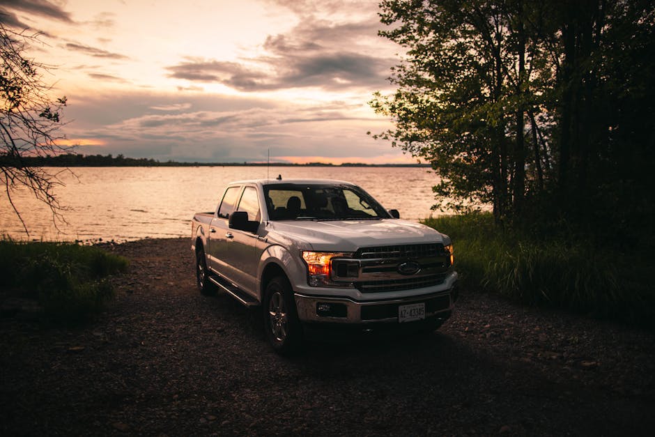 Scenic view of a Ford F-150 truck by a lakeshore in Quebec City at sunset, showcasing the beauty of rural Canada.