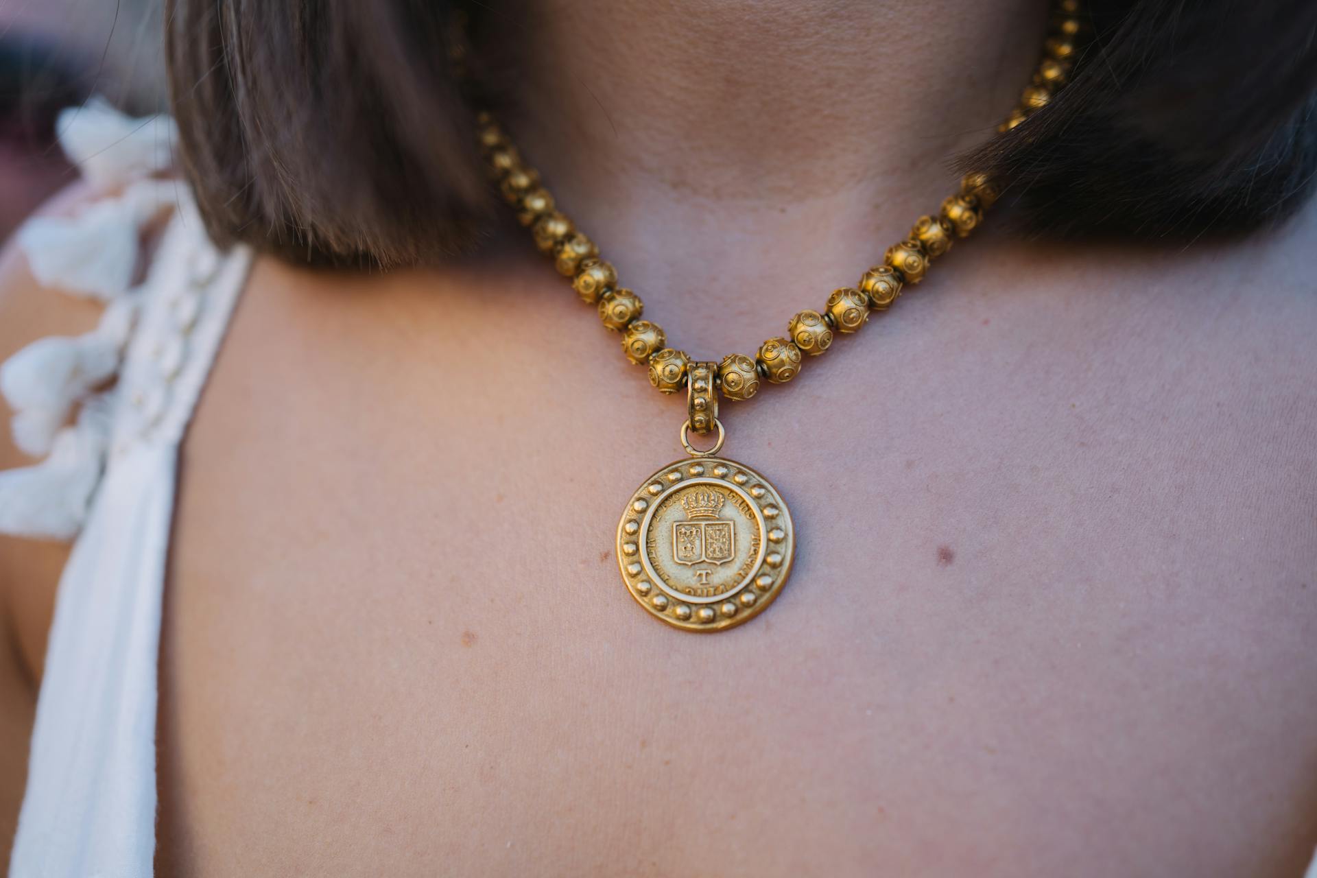 Close-up of an elegant gold necklace with a medallion pendant adding luxury and charm.