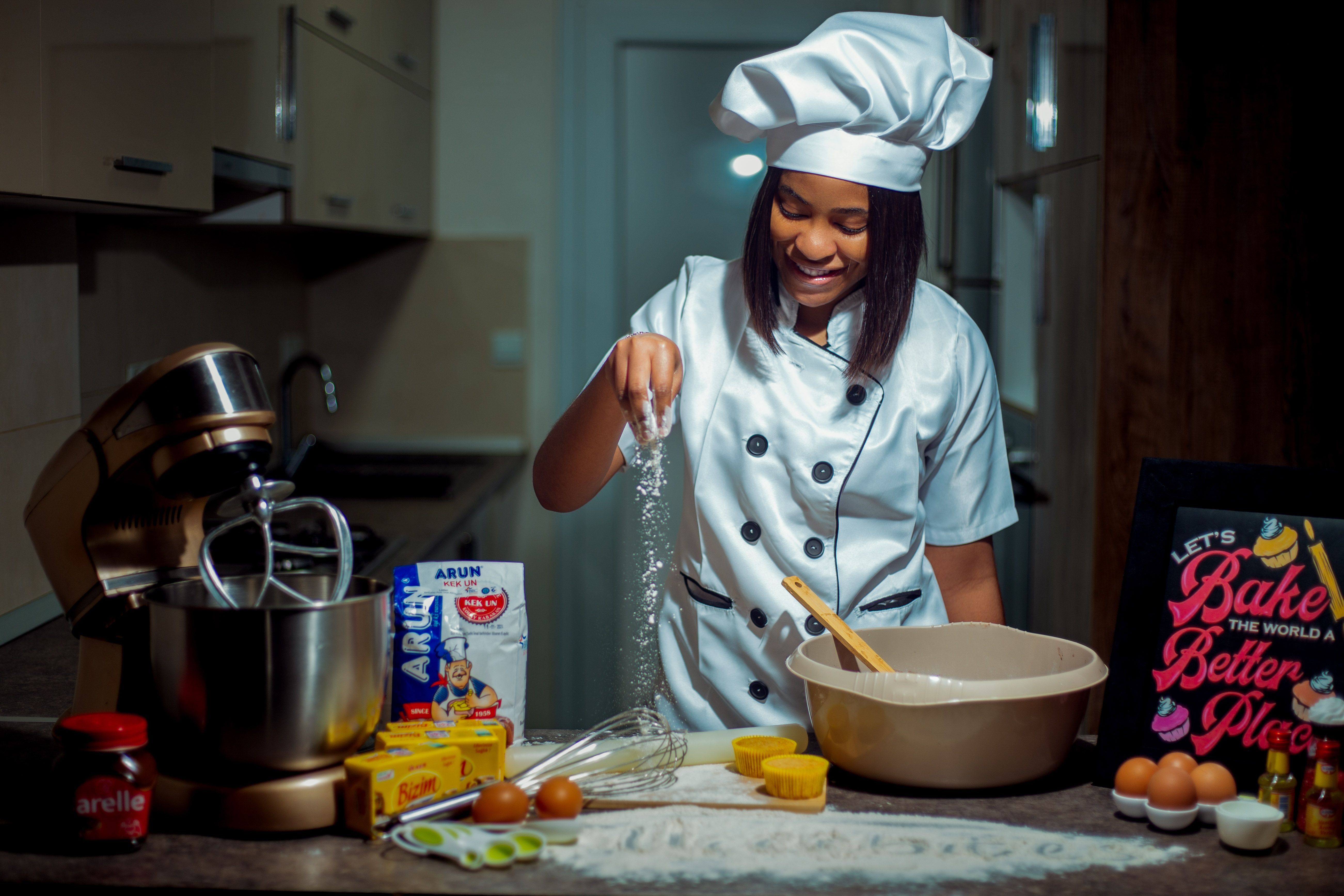 A young chef in a modern kitchen preparing dough with various baking ingredients.