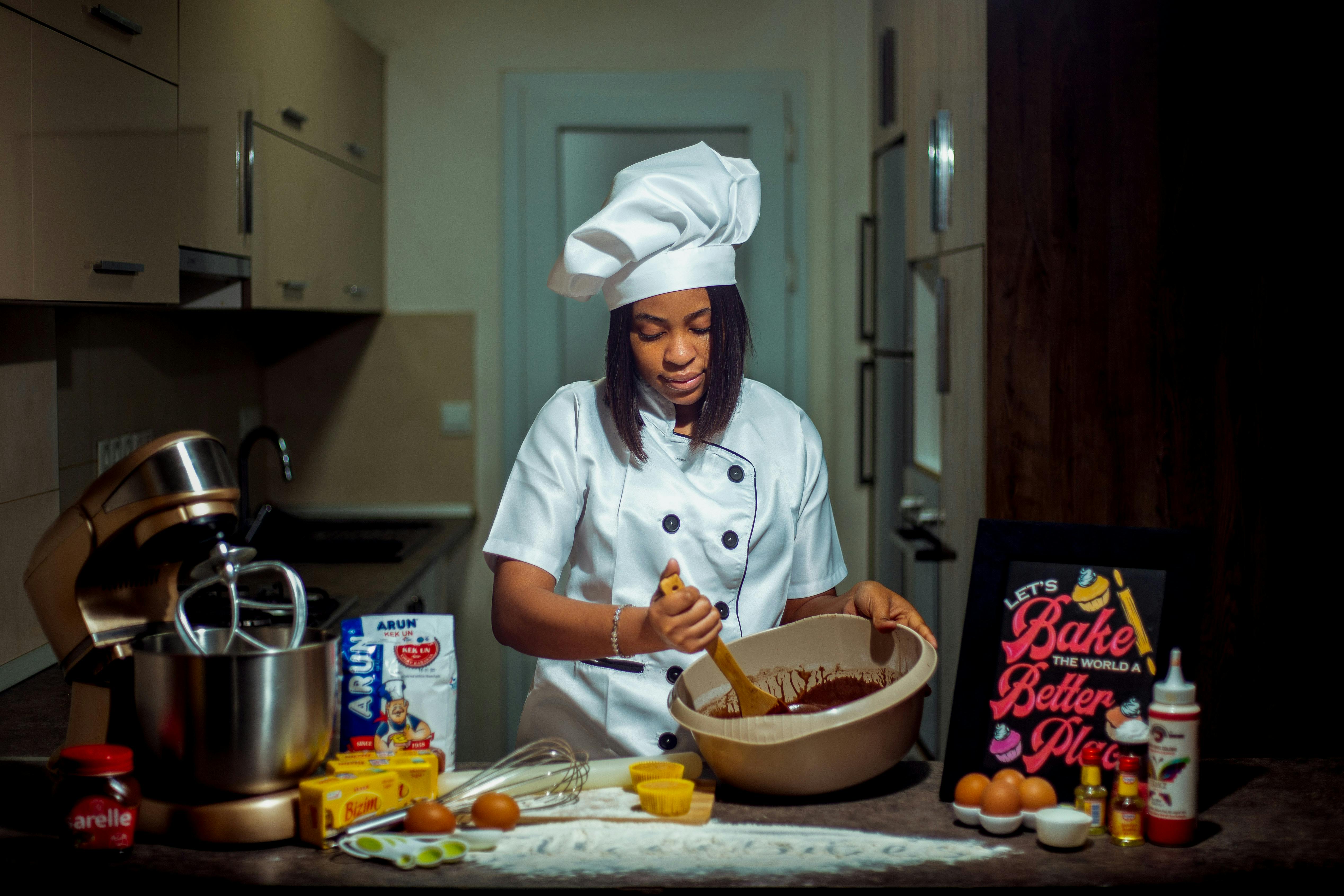 A chef in a kitchen preparing a chocolate cake with various ingredients.