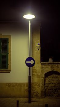 Illuminated street scene featuring a lamp and right arrow sign at night.