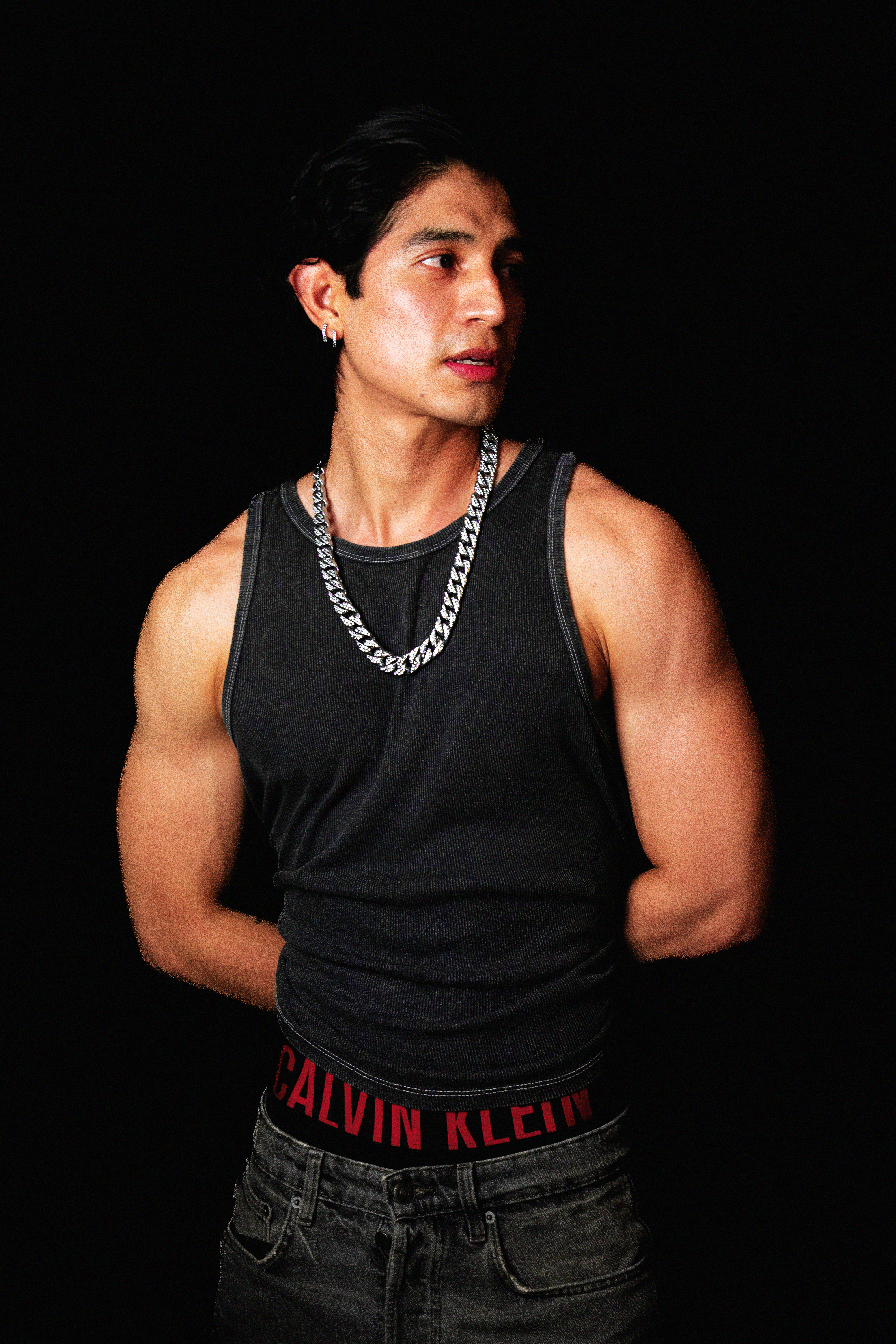 Stylish portrait of a muscular young man in a dark tank top, showcasing a contemporary fashion look.