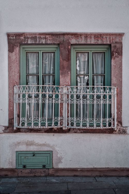 Free A rustic window facade featuring aged green frames and decorative railing, evoking vintage charm. Stock Photo