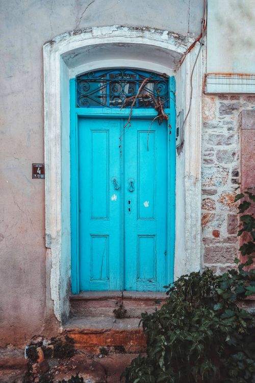 Free A rustic blue wooden door with ornate details set in an aged stone wall, evoking vintage charm. Stock Photo