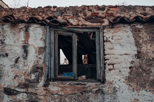 Free A close-up of a decaying wall with a broken window, showcasing urban decay. Stock Photo