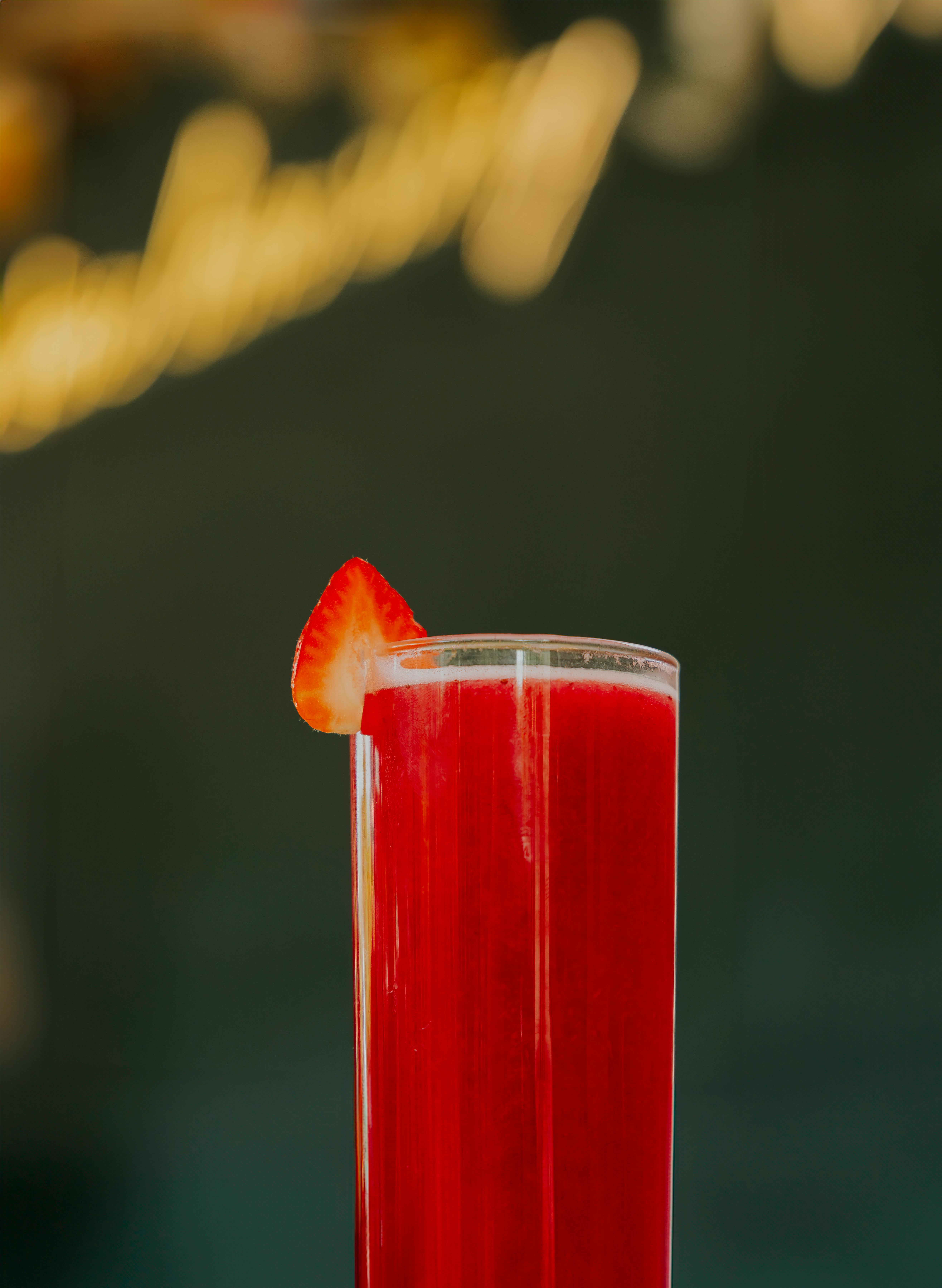 A vibrant red strawberry cocktail served in a tall glass with a fresh strawberry garnish, ideal for summer.