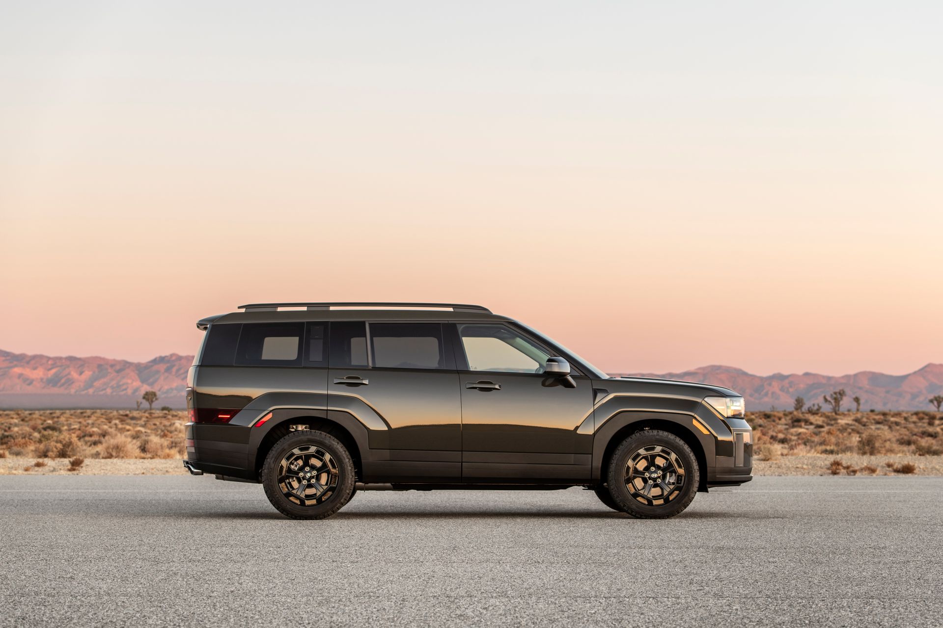 The right side view of the Hyundai SANTA FE XRT stopped with the mountains under the sunset in the background.