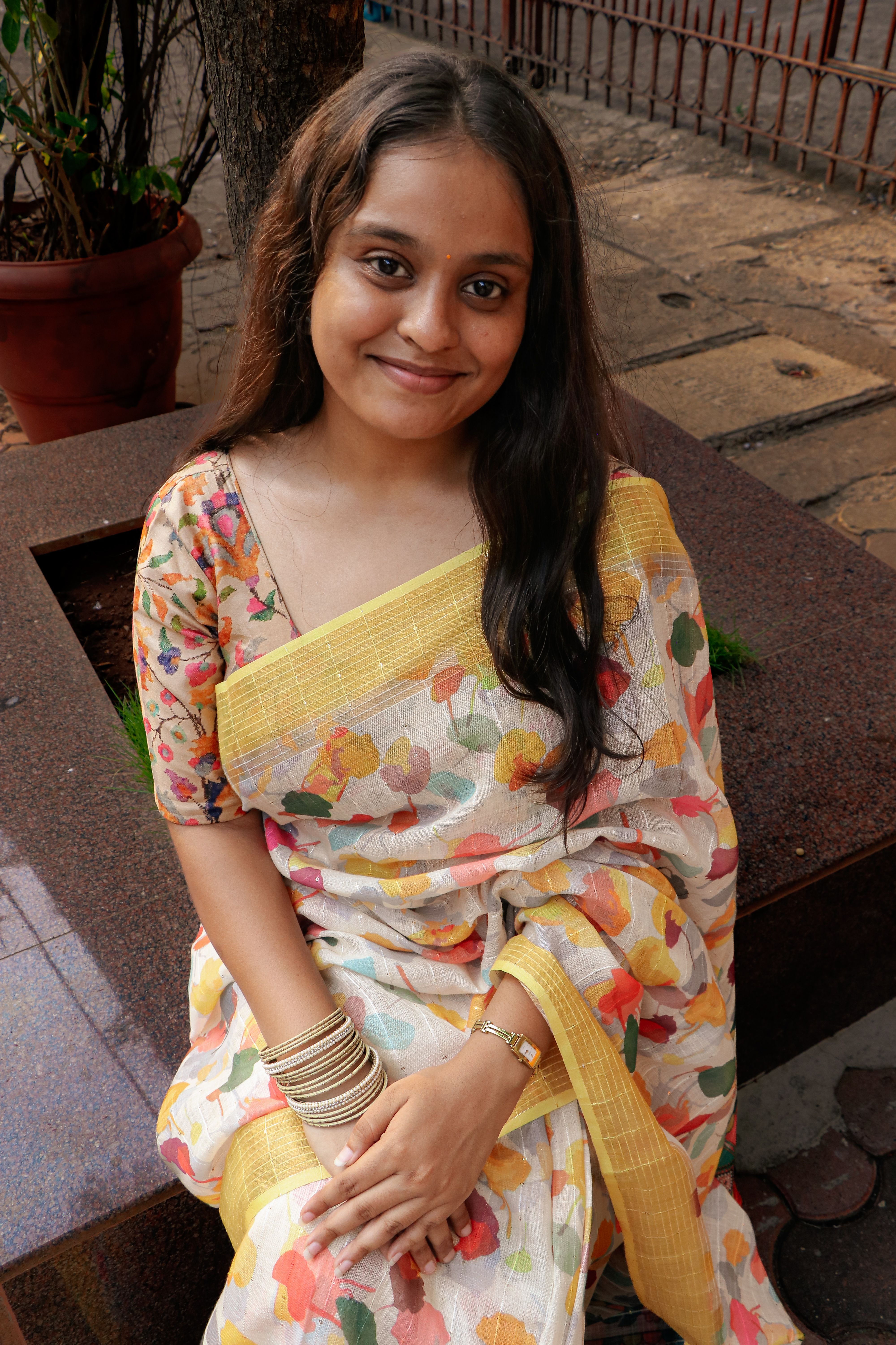 A cheerful woman in a floral saree, enjoying a sunny day outdoors.