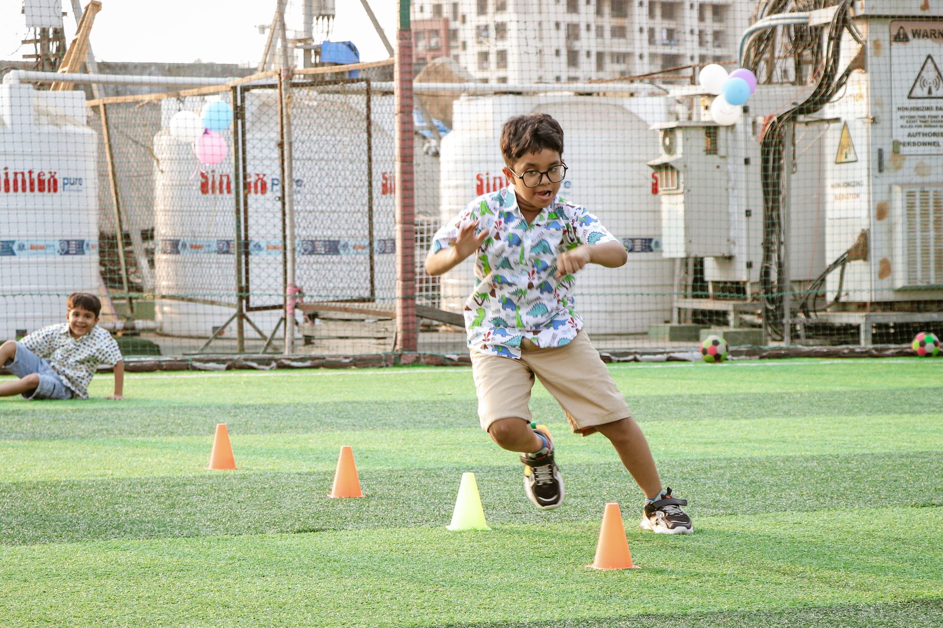 Boys having fun in an outdoor soccer game with cones and sports equipment.