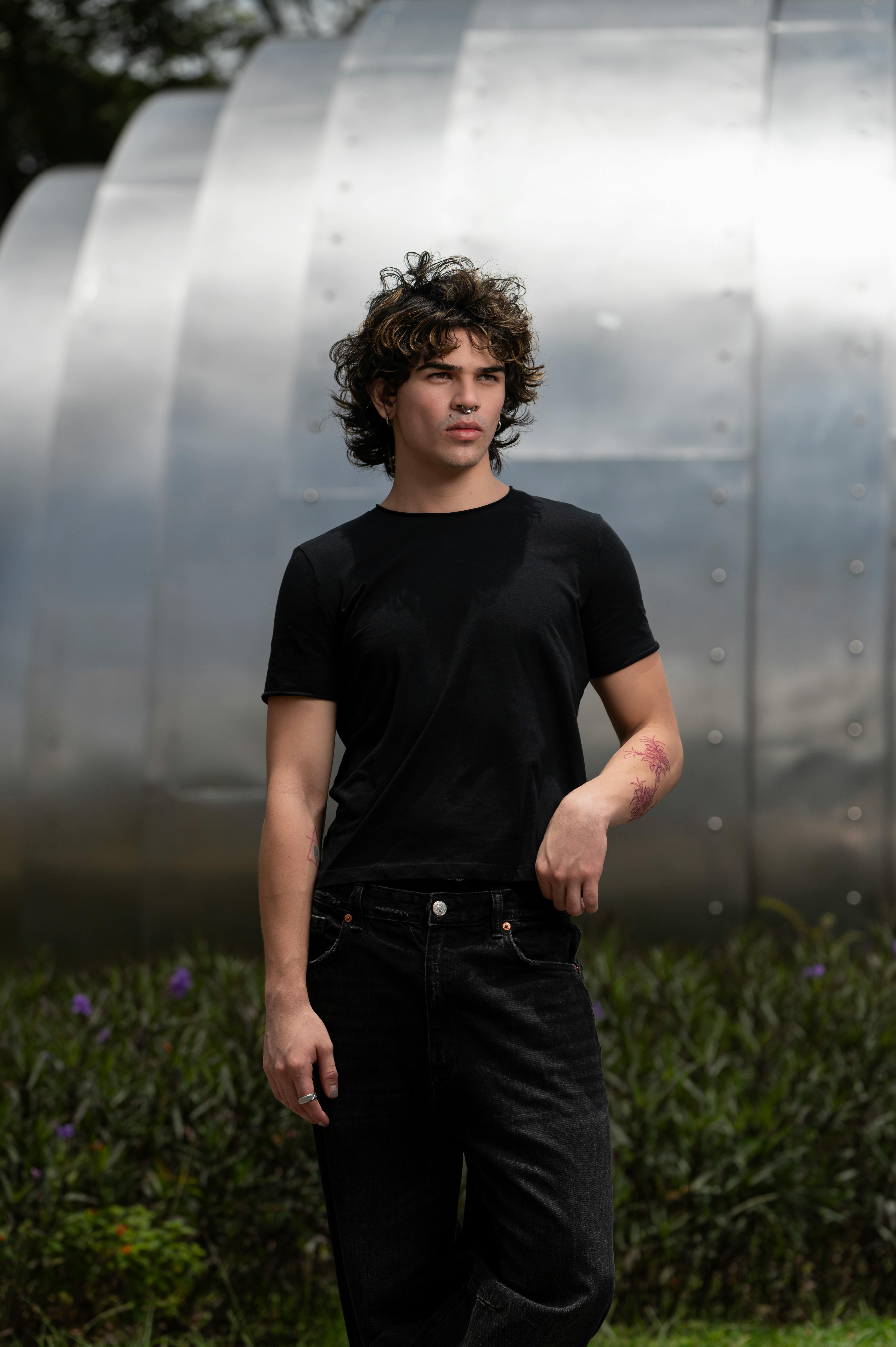 a man in black shirt and jeans standing in front of a metal structure