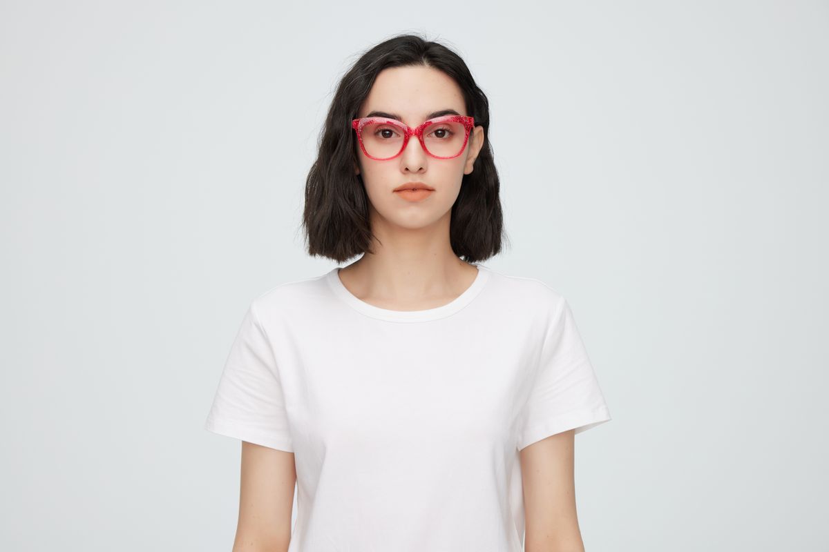 Una mujer joven con camisa blanca luciendo unas gafas de montura roja