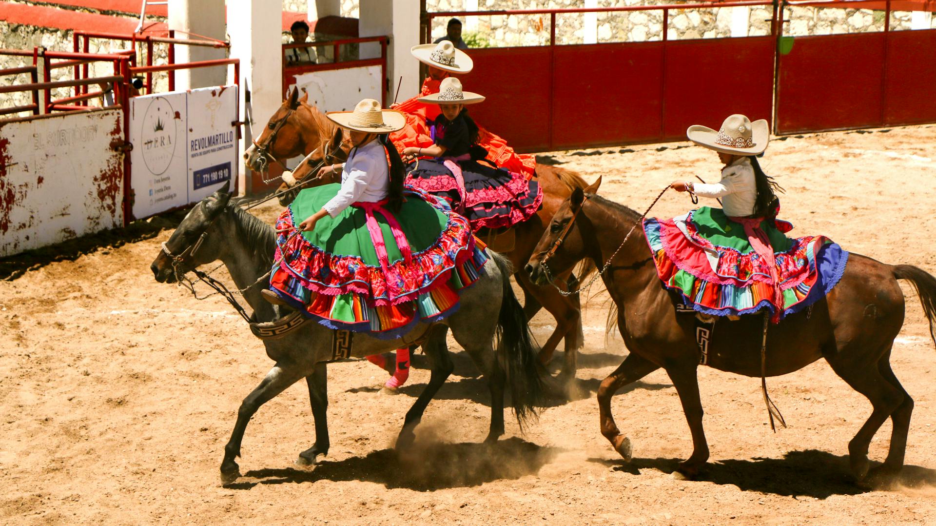 Three women riding horses in a rodeo arena