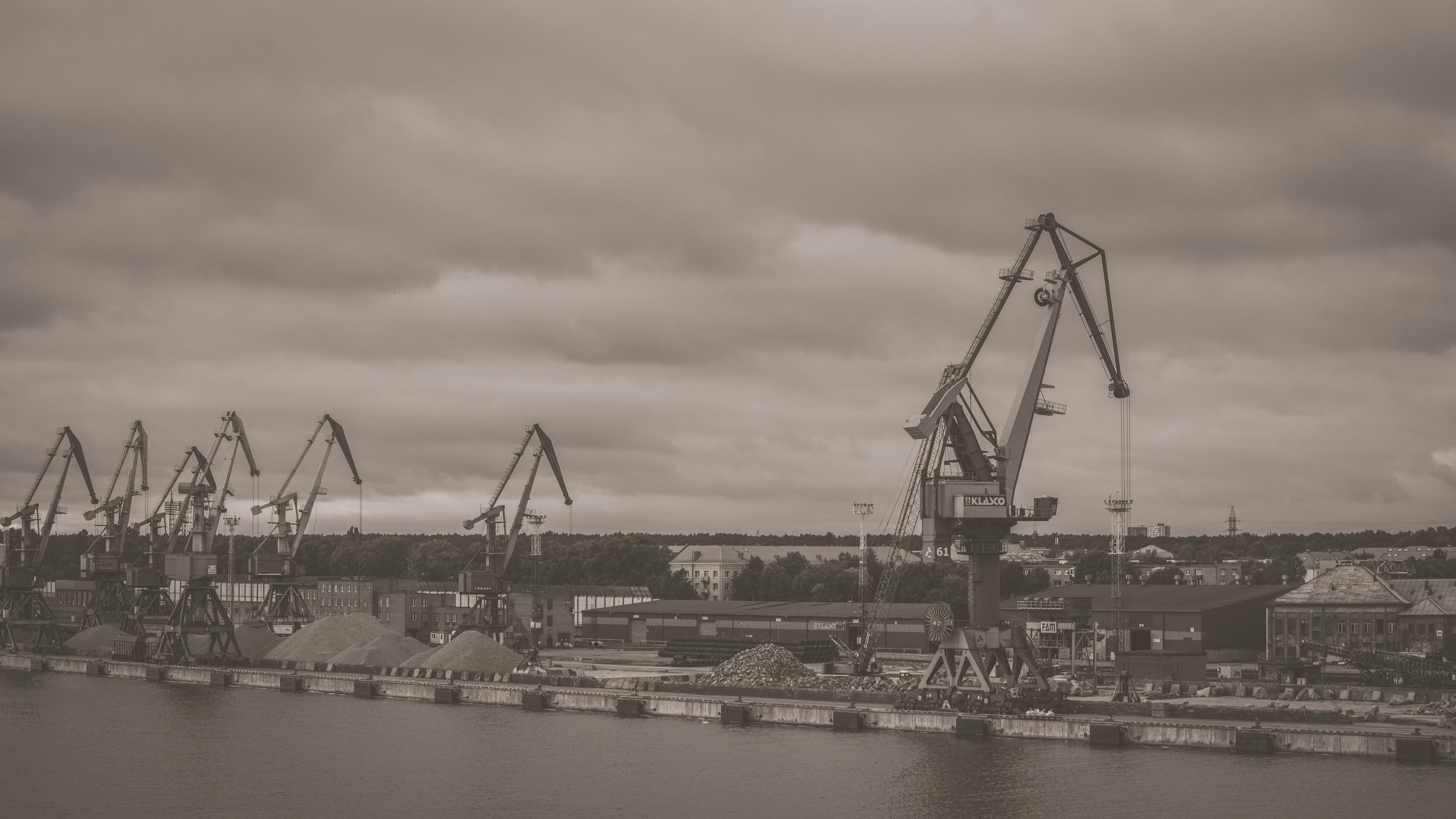 Monochrome view of cranes and machinery at Klaipėda port on a cloudy day.