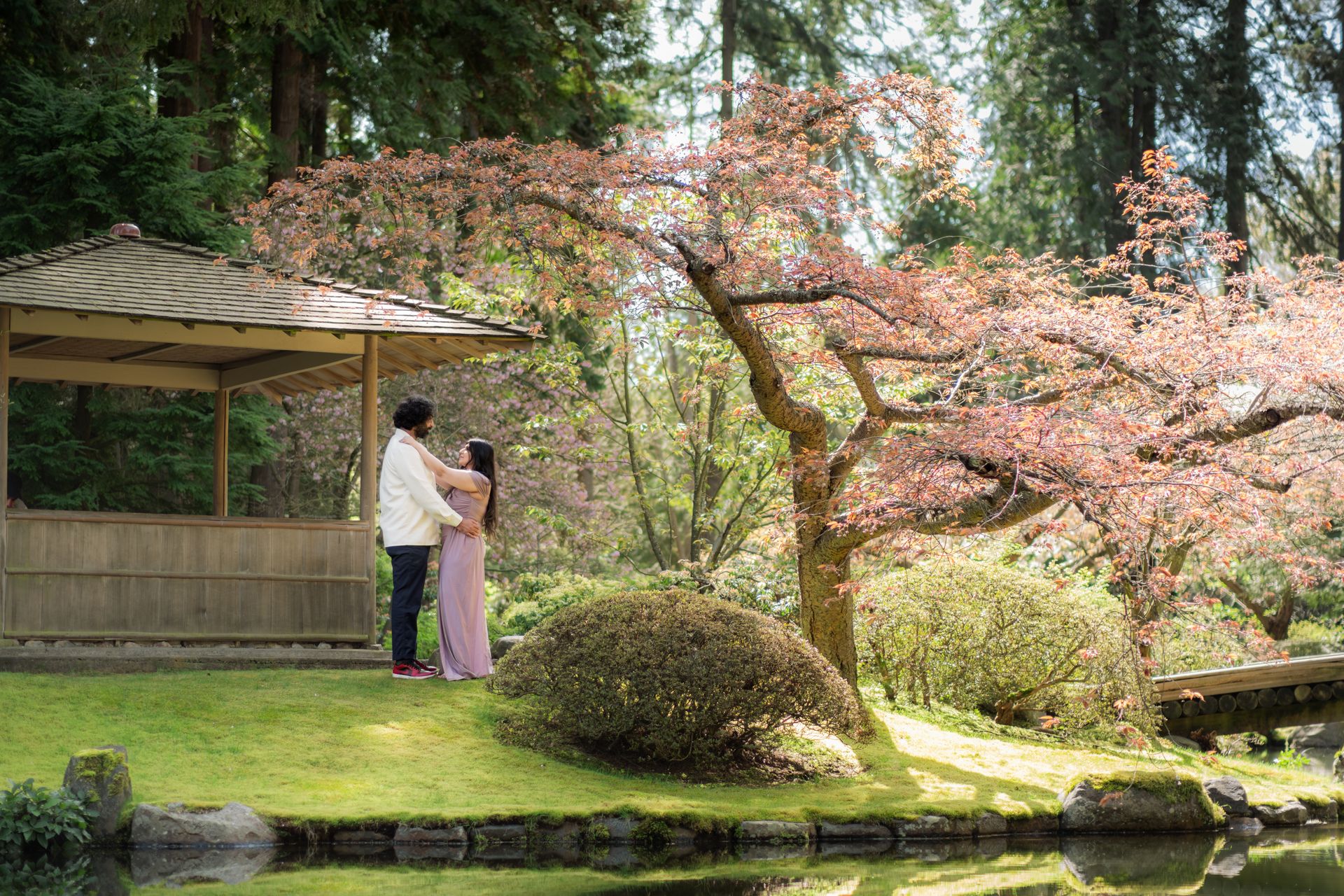 A loving couple embracing in a picturesque Japanese garden in Vancouver during spring.