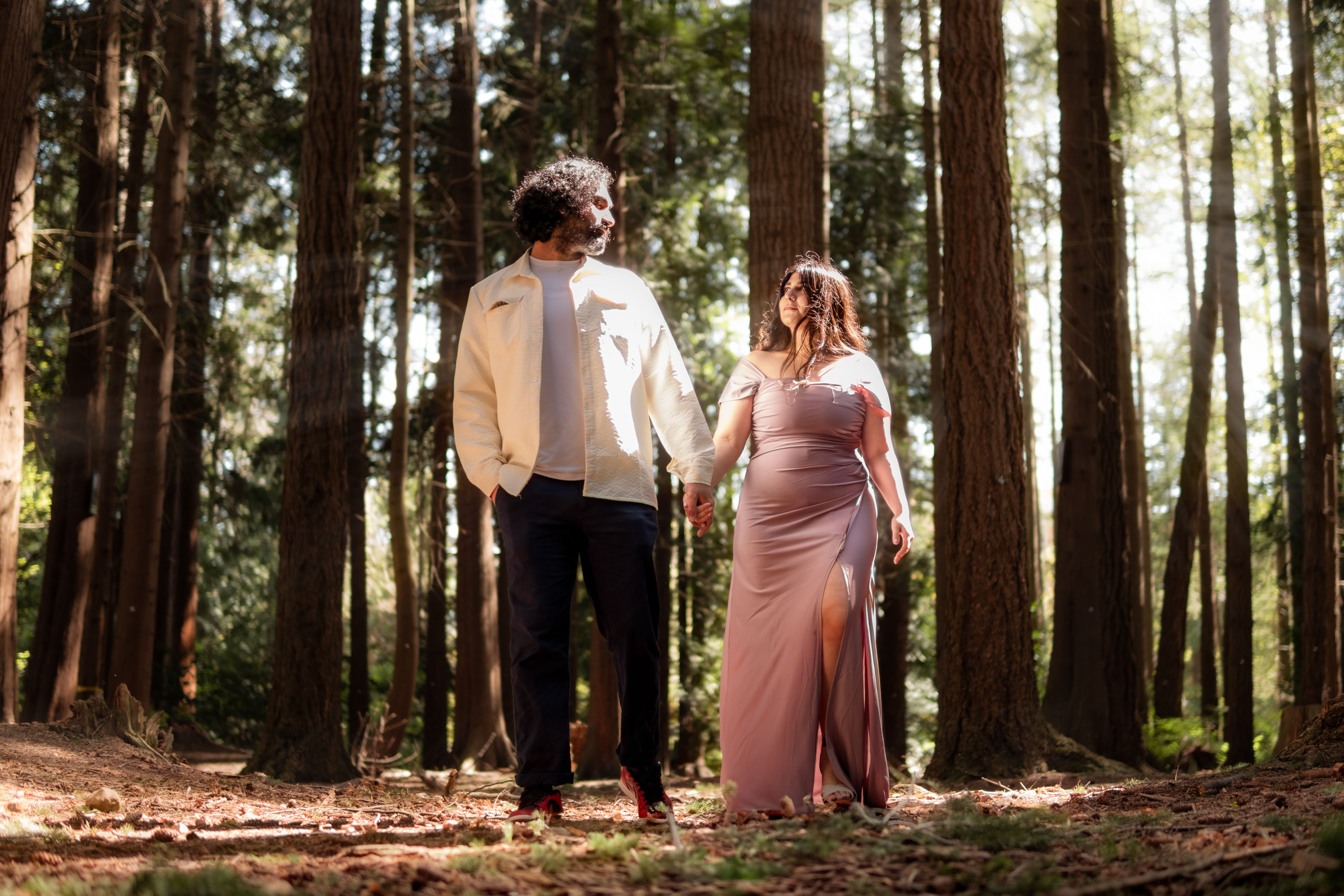 Couple enjoying a romantic walk in Vancouver's lush forest, surrounded by tall trees.