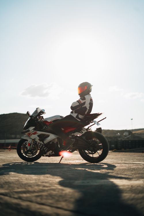 Free A motorcyclist in full gear poses on a sports bike with the sun shining in the background. Stock Photo