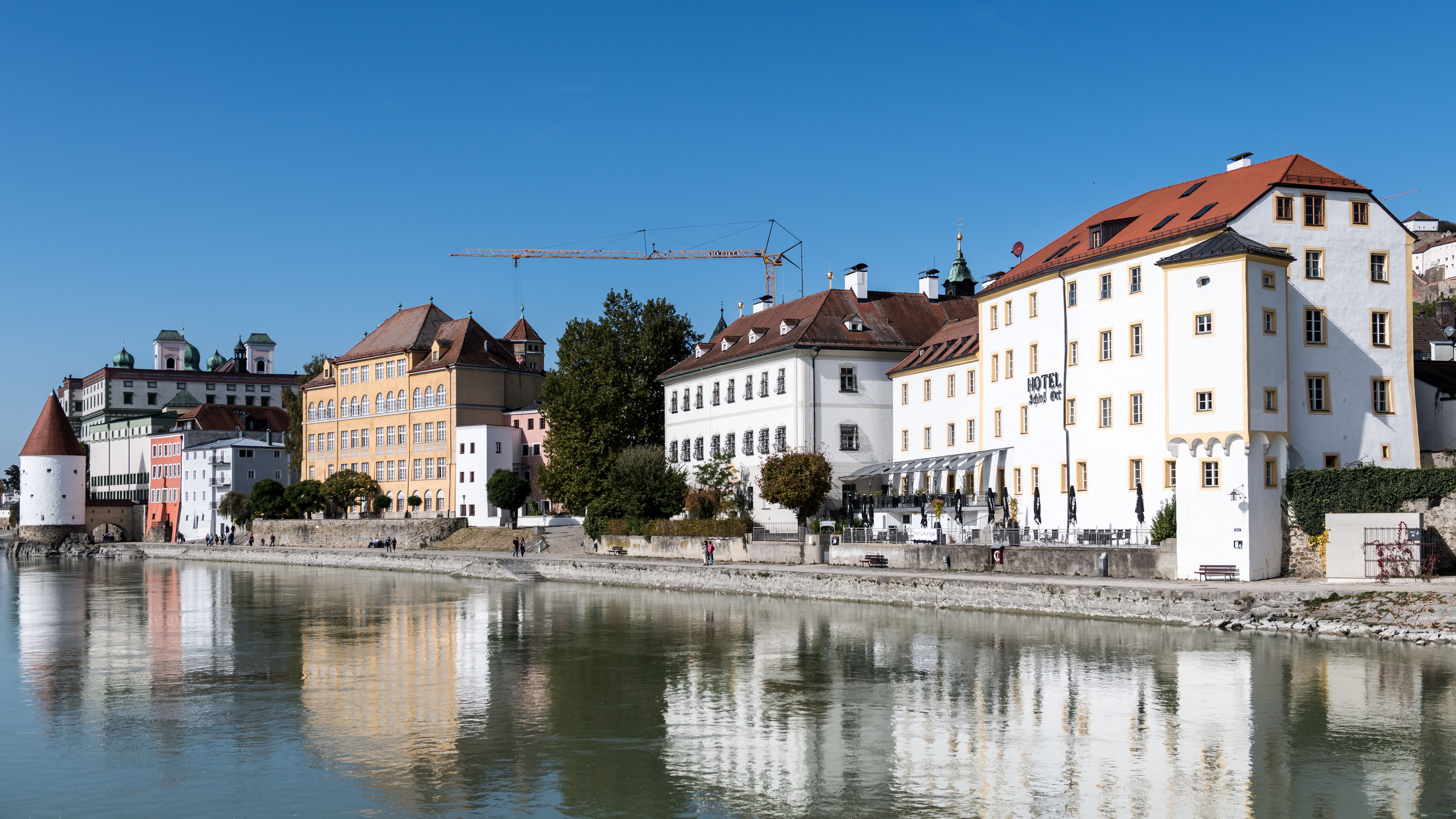 Serene daytime view of Passau's historic waterfront buildings reflecting on the Danube River.
