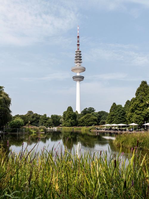 Free Serene view of Hamburg's Fernsehturm reflecting in a tranquil lake with lush greenery. Stock Photo