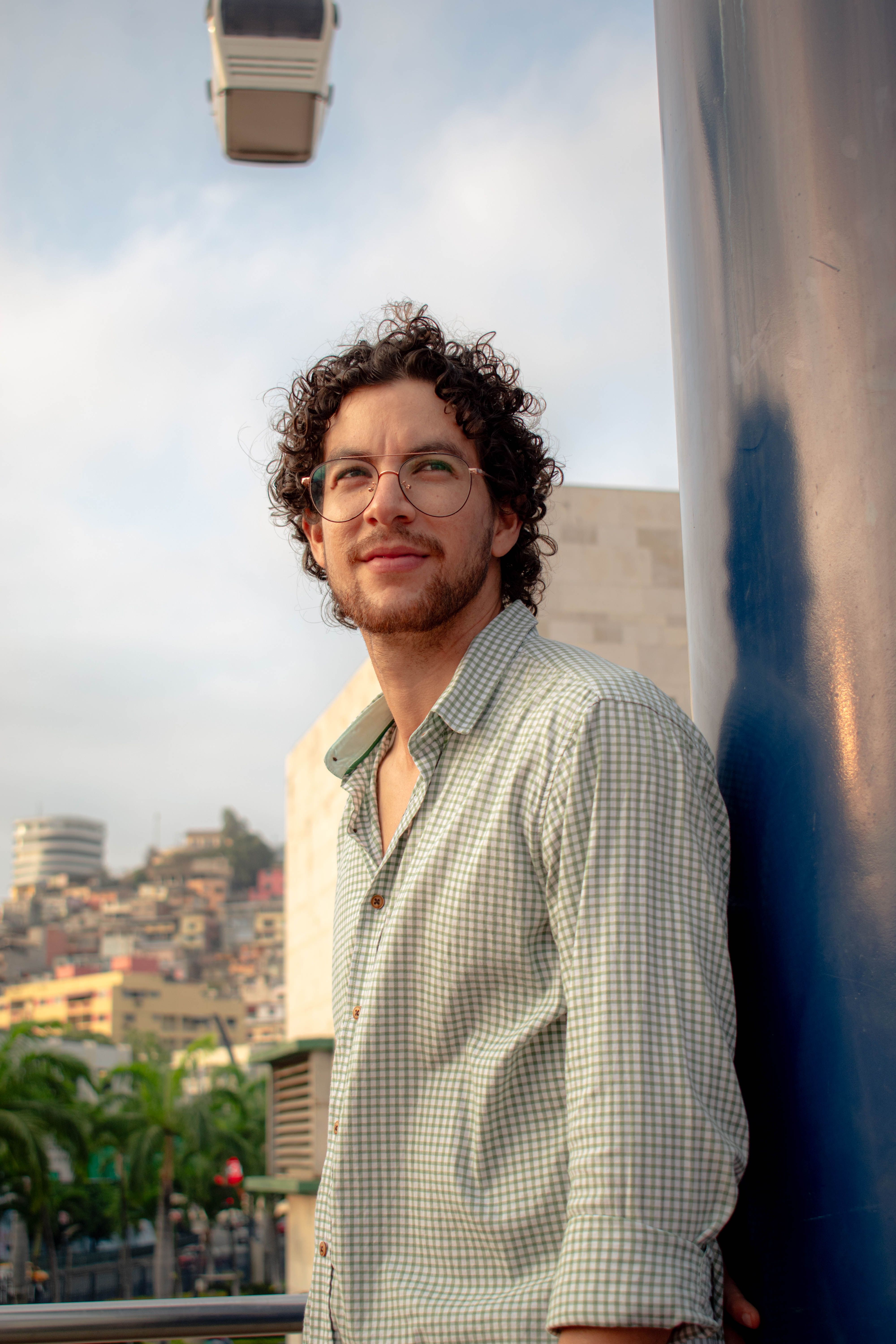 Confident man in stylish attire posing against a vibrant urban cityscape during the day.