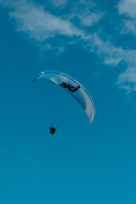 A paraglider soaring in the clear blue sky over La Réunion, capturing the essence of adventure and freedom.