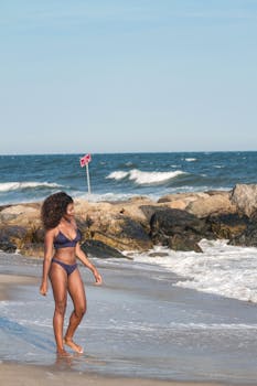 一名女子穿着比基尼，在岩石海岸享受阳光明媚的日子