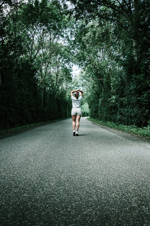 Mujer En Camiseta Blanca Caminando Por La Carretera De Hormigón