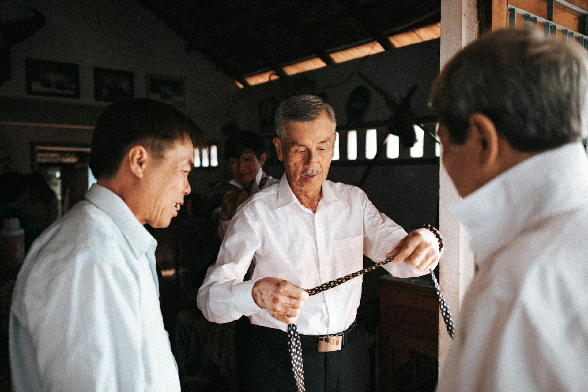 Two men are looking at a knife while another man is holding a knife