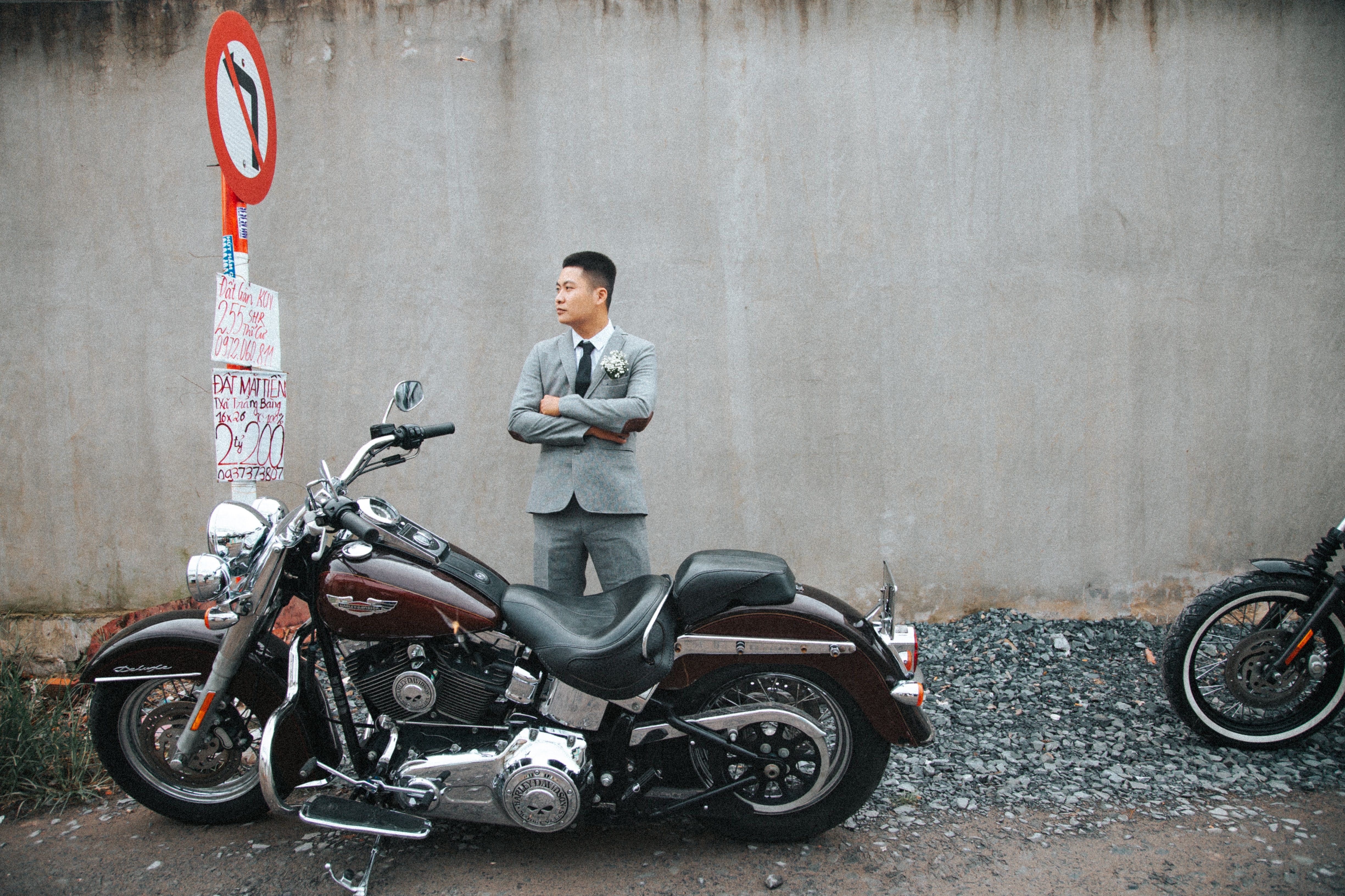 Free A man in a suit stands confidently by a motorcycle in an urban environment. Stock Photo