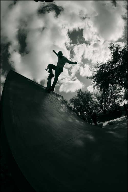 Free Silhouette of a skateboarder performing a trick on a ramp against a cloudy sky in an outdoor skate park. Stock Photo