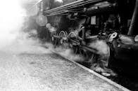 一张蒸汽机车在火车站冒烟的单色照片