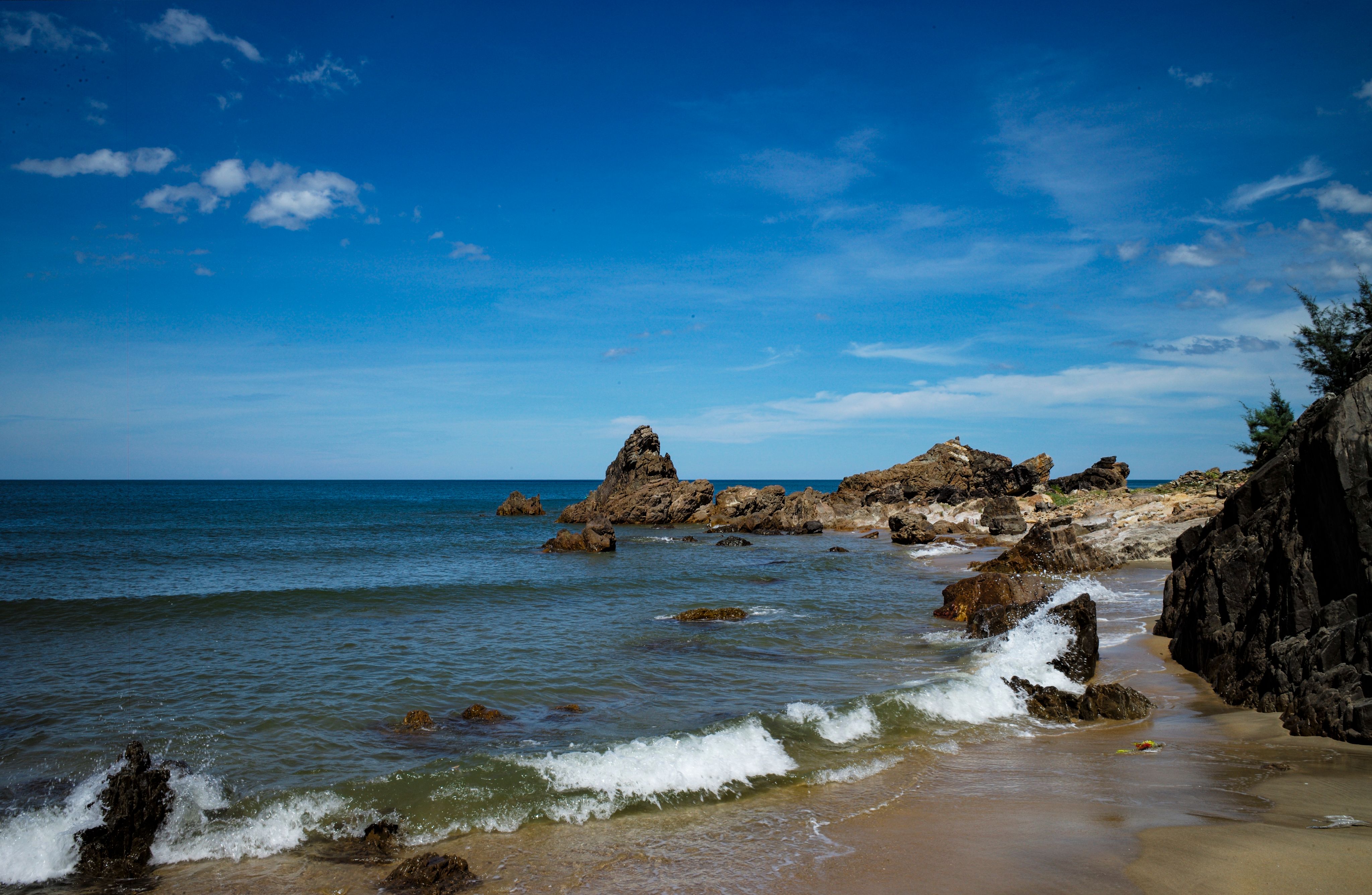A beach with waves and rocks in the ocean · Free Stock Photo