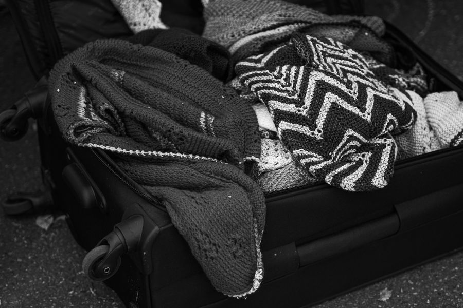 Monochrome photo of knitted clothes in an open suitcase, showcasing texture and warmth.