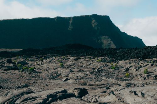 Free View of a rugged volcanic landscape with distant cliffs in La Réunion, France. Stock Photo