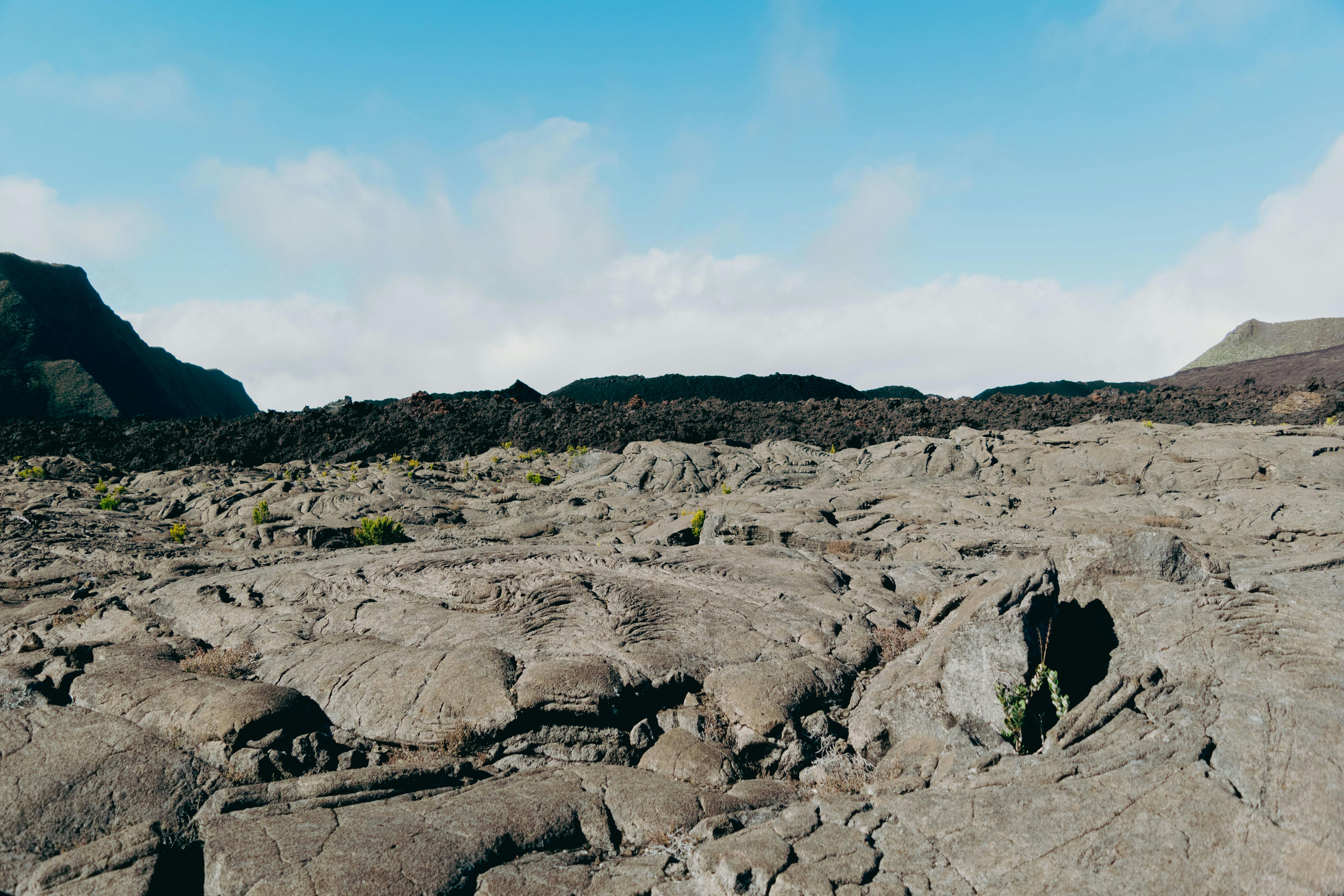 a person standing on a rocky hill with a blue sky