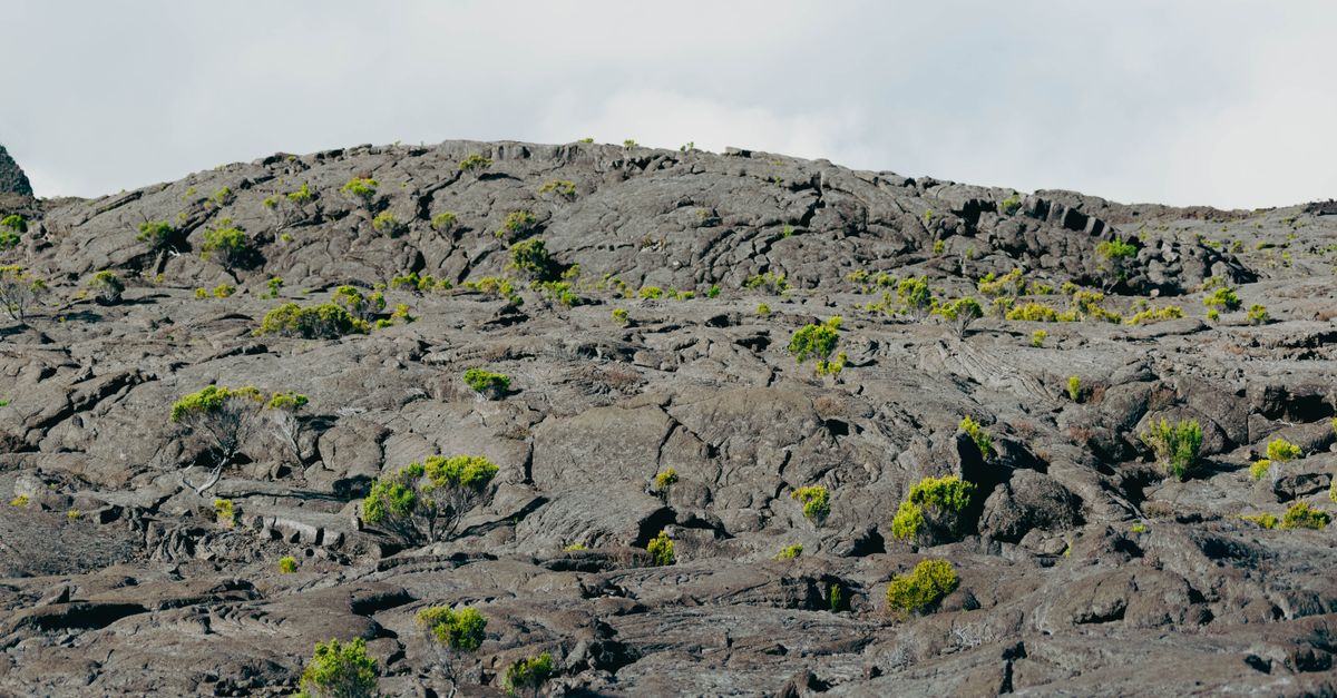 Senderista con el movil y una eSIM para la Isla de la Reunion ante el volcan Piton de la Fournaise